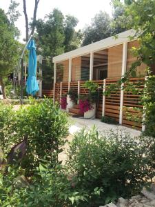 a house with a porch with a blue umbrella at Campsite Sunny Home Soline in Biograd na Moru