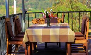 a table with a vase of flowers on a balcony at Lake Mulehe Gorilla Lodge in Kisoro