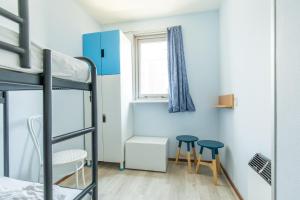 a dorm room with bunk beds and two stools at Appartement De Parel, Resort Amelander Kaap in Hollum +27 photos