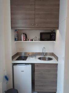 eine kleine Küche mit einer Spüle und einer Mikrowelle in der Unterkunft Enjoyable 20m² MONTREUIL 5 minutes Paris in Montreuil