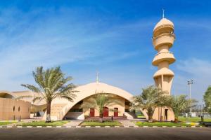 a mosque with a tower in front of a building at Officers Club & Hotel in Abu Dhabi