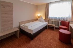 um quarto de hotel com uma cama e uma cadeira em Hotel Pfefferburg em Schönaich