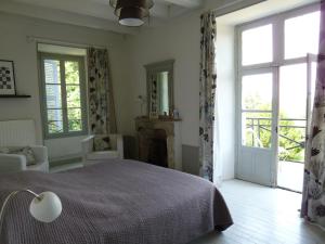 a bedroom with a bed and a fireplace and windows at Le Prieuré in Lézigné