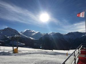 a view of a snowy mountain with the sun in the sky at Restaurant Fleschboden in Rosswald