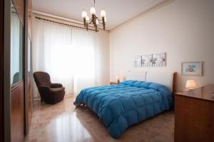 Un dormitorio con una gran cama azul y una silla en Casa Giolele, en Acireale