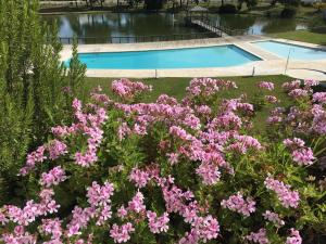 un jardín con flores rosas y una piscina en Soltroia Beachouse, en Tróia