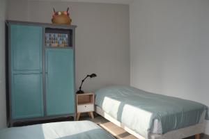 a bedroom with a bed and a blue cabinet at Le Cottage in Harbonnières