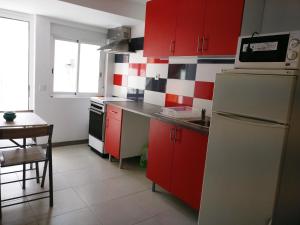 a kitchen with red cabinets and a white refrigerator at Casa da Figueira Da Foz in Figueira da Foz