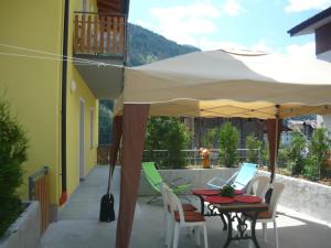 a patio with a table and chairs under an umbrella at Appartamenti Mosconi Mistica in Vermiglio