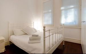 a bedroom with a white bed with towels on it at Gorgeous Subiaco cottage in Perth