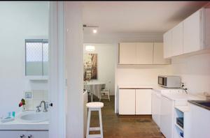 a white kitchen with a sink and a microwave at Gorgeous Subiaco cottage in Perth