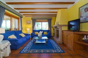 ein Wohnzimmer mit einem blauen Sofa und einem TV in der Unterkunft Villa Cantallops in Jávea