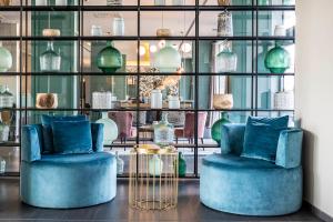 a room with two blue chairs and glass shelves with vases at Vincci Maritimo in Barcelona