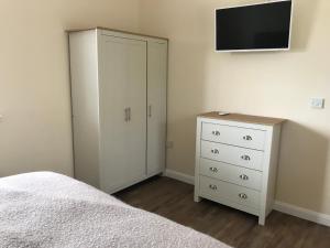 a bedroom with a white cabinet and a tv at Spring Hill Cottages in Towcester