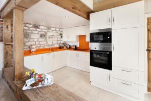 cocina con armarios blancos y pared de piedra en The Old Dairy, Heritage Escapes, Field House Farm, en Bempton 12 fotos más