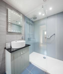Un baño con lavabo y ducha de cristal. en The Old Dairy, Heritage Escapes, Field House Farm, en Bempton