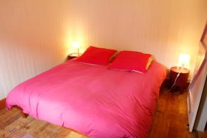 マルシアックにあるLa Maison WOAN centre de Marciacの大型ピンクベッド1台(赤い枕2つ付)が備わるベッドルームです。