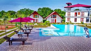 a resort with a pool and tables and umbrellas at Santon Resort & Spa - Level 1 Certified in Tangalle