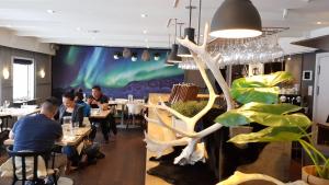 people sitting at tables in a restaurant with an aurora mural at Backcountry Hotel Sisimiut in Sisimiut