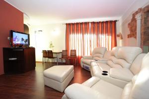 sala de estar con muebles blancos y TV de pantalla plana en Atgiris, en Palanga