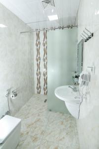 a white bathroom with a sink and a shower at Evim Otel in Zaqatala