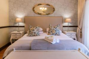 a bedroom with a large bed with two lamps and a mirror at Berluda Farmhouse and Cottages in Oudtshoorn