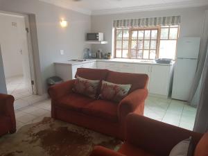 a living room with a couch and a kitchen at Settler Cottage Apartment in Grahamstown