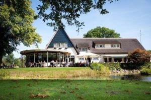 a large white house with people sitting on the lawn at Hotel Restaurant Het Witte Huis in Olterterp