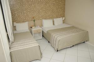 a room with two beds and a table with a night stand at Serra Plaza Hotel in Serrinha