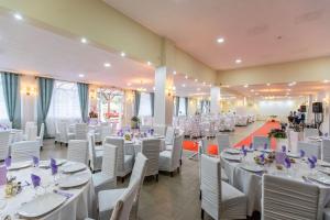 a banquet hall with white tables and white chairs at Pensiune Perla - Bistrița Năsăud in Susenii Bîrgăului