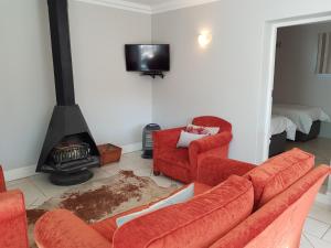 a living room with two red chairs and a fireplace at Settler Cottage Apartment in Grahamstown