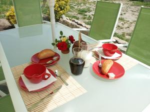 a table with red plates and cups and food on it at Les Chambres d'Helix in Saint-Dizier-les-Domaines
