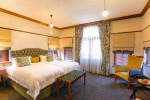 una habitación de hotel con una cama grande y una silla en Eendracht Hotel en Stellenbosch