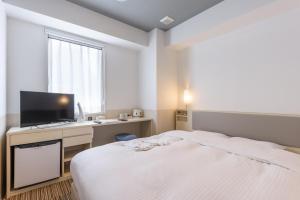 a bedroom with a bed and a desk with a television at Belken Hotel Kanda in Tokyo
