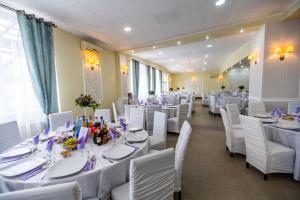 a banquet hall with white tables and white chairs at Pensiune Perla - Bistrița Năsăud in Susenii Bîrgăului
