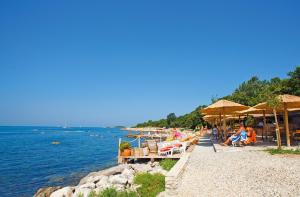 a beach with chairs and umbrellas and the water at Caravans Bijela Uvala in Poreč