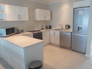 a kitchen with white cabinets and a refrigerator at Laguna Grove Holiday Rentals in Knysna