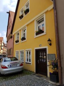 ein gelbes Haus mit einem davor geparkt in der Unterkunft Lindes Ferienwohnung in Dinkelsbühl