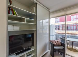 ラスパルマス・デ・グランカナリアにあるCanteras Little Gemのテレビ、椅子、テーブルが備わる客室です。