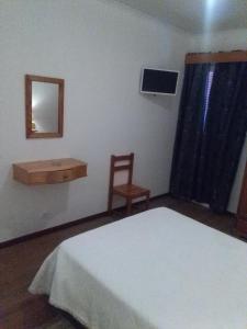um quarto com uma cama, um espelho e uma cadeira em AL Moniz em Machico