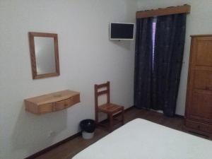 a room with a bed, chair and a tv at AL Moniz in Machico