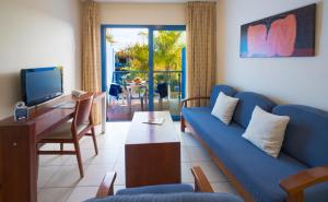 a living room with a blue couch and a tv at BLUESEA Jandia Luz in Morro del Jable