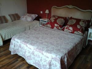 um quarto com 2 camas com lençóis vermelhos e brancos em Chambres d'Hôtes l'Hermine em Val Couesnon