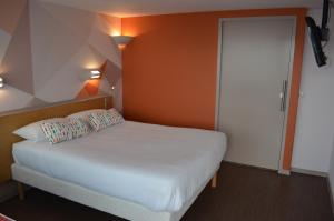 a bedroom with a white bed and an orange wall at initial by balladins La Roche-sur-Yon in La Roche-sur-Yon