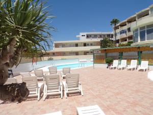 a group of white chairs and a swimming pool at La Colina in San Agustin