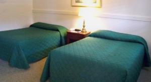 two beds in a hotel room with green comforters at Mount Whittier Motel in Center Ossipee