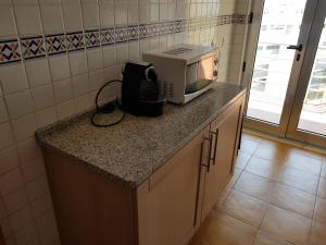 een magnetron op een aanrecht in een keuken bij Encosta da Marina Residence in Portimão