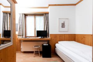 a bedroom with a bed and a desk with a computer at Hotel Bären in St. Moritz