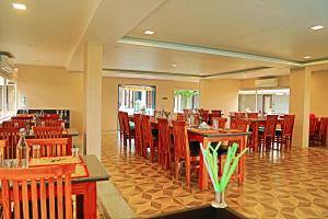 a dining room with wooden tables and chairs at Athena Hotel in Tiruvannāmalai