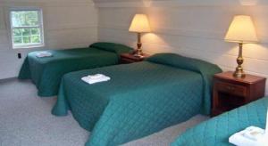 a hotel room with three green beds and lamps at Mount Whittier Motel in Center Ossipee